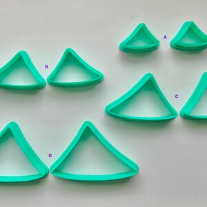 May include: Set of six turquoise plastic triangle cookie cutters in various sizes. The cutters are labeled A, B, C, and D.