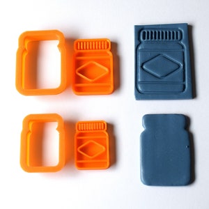 May include: Set of four cookie cutters and two stamps in the shape of a jar. The cutters are orange and the stamps are blue.