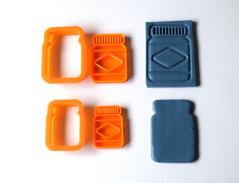 May include: Set of four cookie cutters and two stamps in the shape of a jar. The cutters are orange and the stamps are blue.