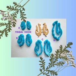 Peut inclure: Ensemble de six emporte-pièces en plastique bleu en forme de crochets tribaux et de volutes. Les emporte-pièces sont étiquetés A, B, C et D. Le texte "Tribal Hook" est écrit sur la surface blanche.