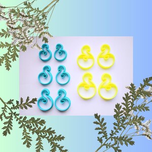 Peut inclure: Six paires de boucles d'oreilles, trois paires sont bleues et trois paires sont jaunes. Les boucles d'oreilles sont en forme de lettre S stylisée.