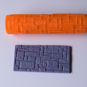 May include: Orange and purple silicone rolling pin and stamp with a brick pattern.