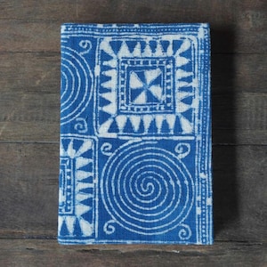 May include: A blue and white fabric notebook cover with a geometric pattern. The cover features a repeating design of circles, squares, and triangles.