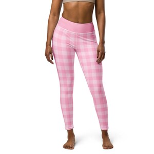 May include: Pink and white plaid leggings. The leggings have a high waistband and a gingham pattern. The fabric appears to be a soft, stretchy material. The leggings are form-fitting and reach to the ankles.