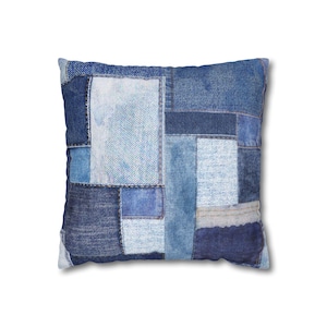 May include: A square throw pillow featuring a patchwork design composed of various shades of blue denim fabric. The surface displays multiple rectangular and square panels of light, medium, and dark wash denim stitched together with visible seams.