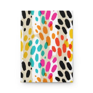 May include: A hardcover journal with a colorful abstract design. The cover features a pattern of black, yellow, orange, pink, and teal brushstrokes on a beige background. The journal is rectangular and appears to be new.