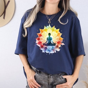 May include: A navy blue t-shirt with a colorful mandala design featuring a person meditating in the center. The mandala is made up of various shades of blue, green, yellow, orange, and red.