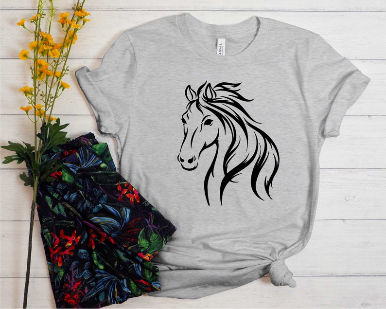 Peut inclure: Un t-shirt gris avec une silhouette noire de t&ecirc;te de cheval sur le devant.