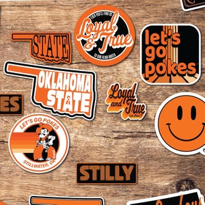May include: A set of 20 Oklahoma State University stickers featuring various designs, including the school mascot, the state outline, and phrases like "Ride 'em Cowboys" and "Let's Go Pokes".