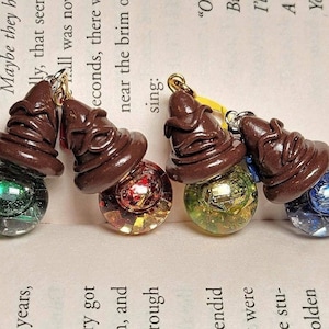 May include: Four brown and black Sorting Hat charms with different colored glass beads. The beads are green, red and gold, yellow and gold, and blue.