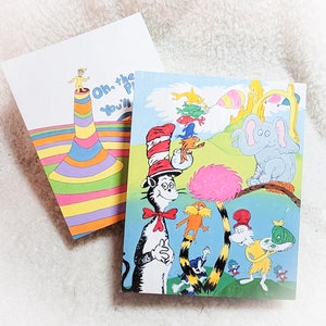 May include: A colorful card featuring the Cat in the Hat and other characters from the book "Oh, the Places You'll Go!" by Dr. Seuss. The card has a bright blue background with a green, yellow, and orange striped hat on the Cat in the Hat. The card also features a pink and white striped hat, a blue and white striped hat, and a red and white striped hat. The card is perfect for a birthday or graduation.