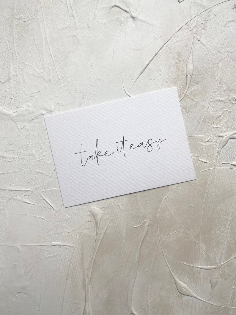Puede incluir: Tarjeta blanca con texto en cursiva negra que dice "take it easy".