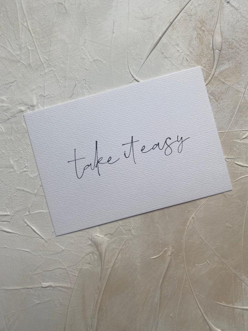 Puede incluir: Una tarjeta blanca con el texto "take it easy" escrito en cursiva negra.