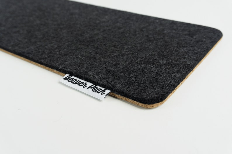 Close up of felt and cork keyboard mat made with black merino wool and showing BeaverPeak logo.