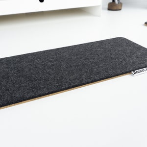 Empty black wool felt keyboard mat on a white desk.