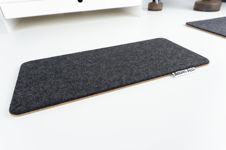 Empty black wool felt keyboard mat on a white desk.