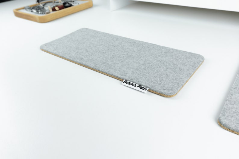 Empty grey merino wool felt and cork keyboard mat on white desk.