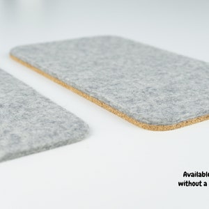 A wool and cork phone mat shown next to our wool only phone mat. Both mats use the same merino wool, but one has an additional layer of anti-slip cork. Both mats are shown in grey merino wool felt.