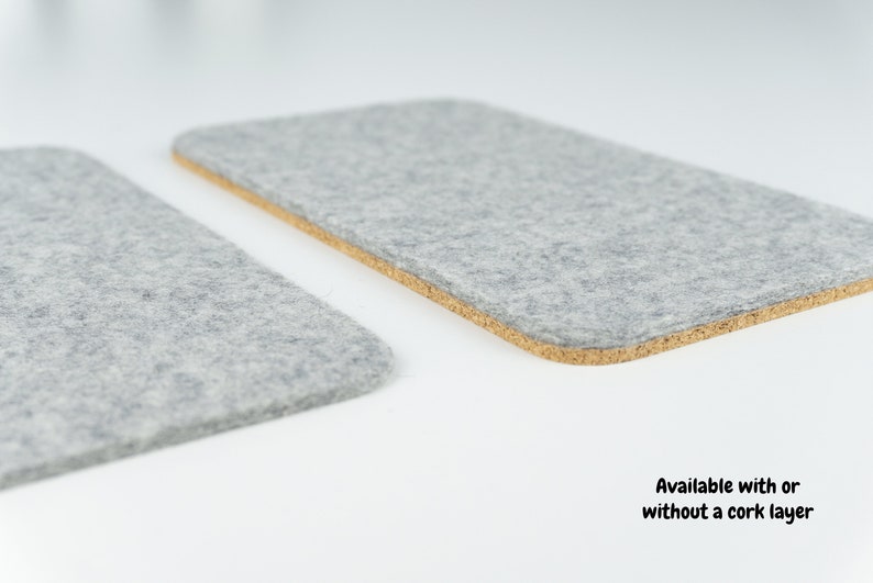 A wool and cork phone mat shown next to our wool only phone mat. Both mats use the same merino wool, but one has an additional layer of anti-slip cork. Both mats are shown in grey merino wool felt.