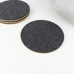 A set of our round black wool felt and cork coasters shown on a white coffee table.