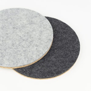 A colour comparison between black and light grey shades of our round wool felt and cork coasters.