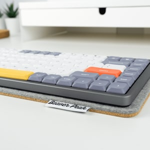 Grey wool felt keyboard mat on desk with Nuphy Air75 mechanical keyboard on top.