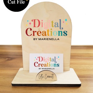 May include: A wooden business card holder with an arched top. The top features the text "Digital Creations by Marianella" in colorful letters. The bottom of the holder has a business card with the same text and a small sign that says "Let's Connect!"
