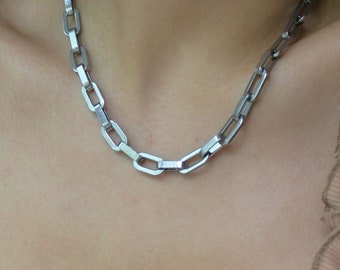 May include: A silver chain necklace with a box chain design.