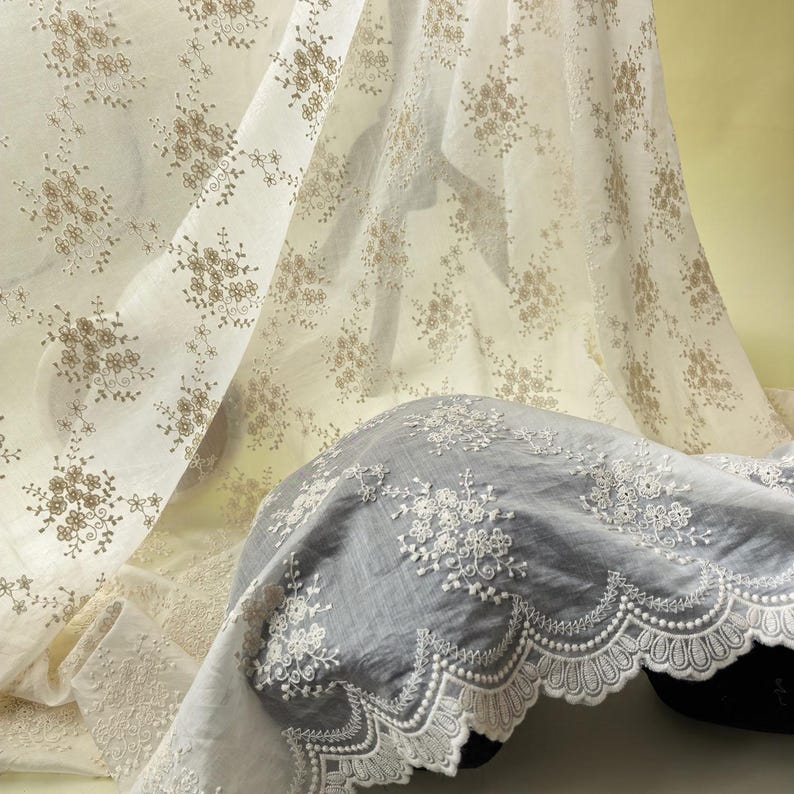 Pu&ograve; includere: Tessuto bianco sporco con un delicato motivo floreale nei toni del marrone. Il tessuto &egrave; drappeggiato, rivelando una sezione di tessuto grigio con intricati dettagli in pizzo bianco sul bordo. L'estetica generale &egrave; morbida ed elegante.