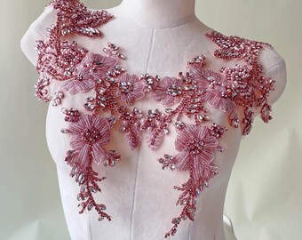 Könnte beinhalten: Staubrosa Perlenapplikation mit floralen und Blattmustern. Die Applikation ist mit funkelnden Strasssteinen und Perlen verziert, wodurch ein zartes und verziertes Design entsteht. Das Design wird auf einer Schaufensterpuppe präsentiert.