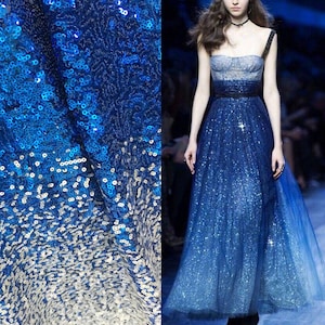 Peut inclure: Gros plan sur un tissu à paillettes bleues avec un effet dégradé, passant du bleu foncé à l'argent. Une mannequin porte une longue robe bleue scintillante avec un dégradé similaire, avec un bustier sans bretelles et une jupe fluide.