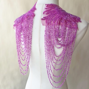 May include: A pair of bright magenta beaded shoulder appliques featuring intricate embroidery and multiple cascading strands of matching beads that drape downward. The design includes a dense floral-like pattern at the top shoulder area.