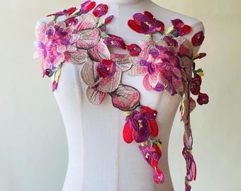 May include: Two floral embroidered appliques. The appliques feature a design of pink, red, and purple flowers with green and yellow accents. The appliques are displayed on a white mannequin. The text "2 Pieces" is visible in the upper right corner.