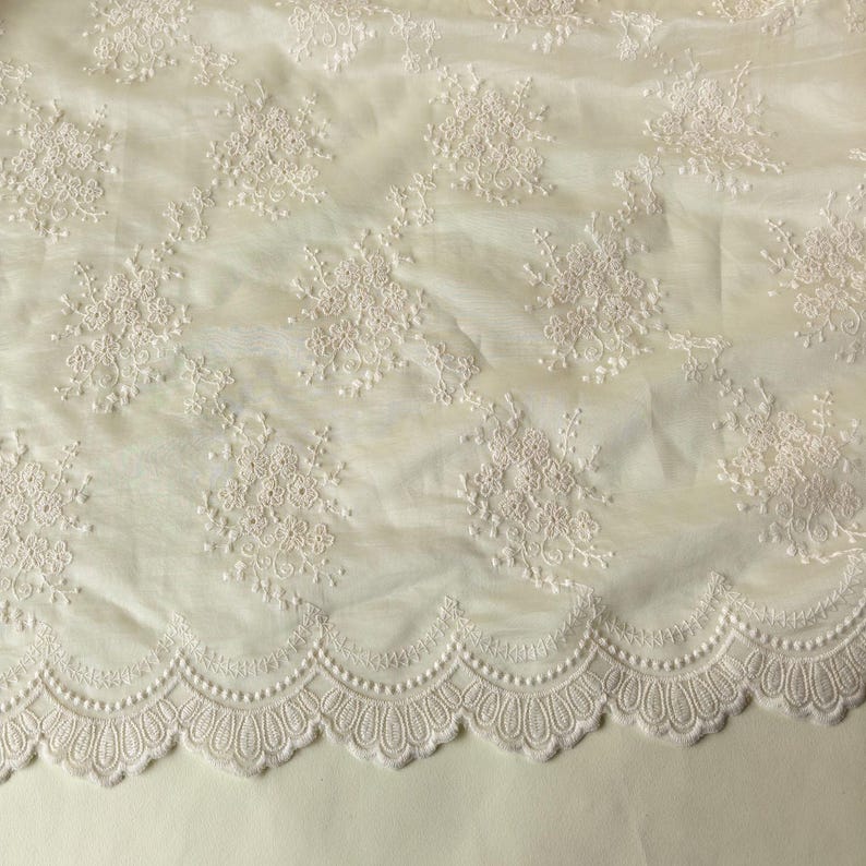 Pu&ograve; includere: Tessuto in pizzo color avorio con ricami floreali. Il tessuto presenta un bordo smerlato con un motivo delicato e ripetuto. Il ricamo &egrave; dettagliato e aggiunge consistenza al materiale morbido e trasparente. Ideale per abiti da sposa, abiti o progetti decorativi.