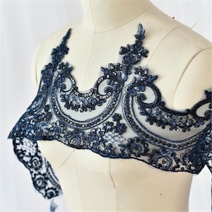 May include: Navy blue lace applique with floral and scrollwork designs. The applique is embellished with sequins and is displayed on a mannequin. This decorative trim is suitable for embellishing garments and accessories.