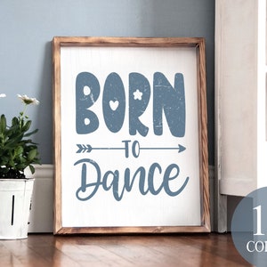 May include: A wooden sign with a distressed blue paint finish. The sign reads "Born to Dance" with a small arrow and hearts.
