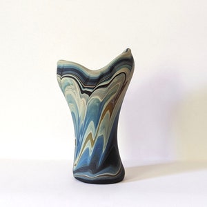 Può includere: Un vaso in ceramica con un design unico e astratto. Il vaso è di colore blu chiaro, grigio e marrone con motivi a spirale.