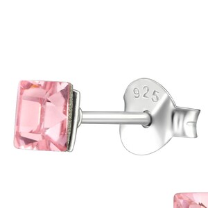 May include: A pair of silver stud earrings with pink square-shaped crystals. The earrings are marked with "925" on the back.