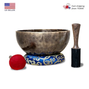 May include: A bronze singing bowl with a blue and gold cushion, a wooden striker, and a red felt mallet. The bowl has Tibetan writing on the inside.