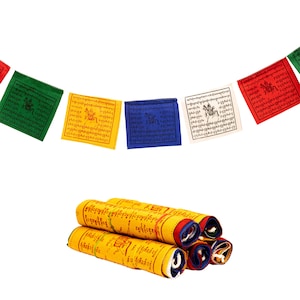 May include: A collection of colorful prayer flags and rolled prayer scrolls. The prayer flags are square, with text and images in various colors, including green, yellow, blue, and red. The rolled scrolls are yellow with red and blue accents.