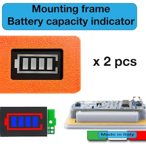 Op de afbeelding: Twee oranje montageframes met een zwarte batterijcapaciteitsindicator die vier balken toont. De indicator is een klein LCD-scherm met een zwarte achtergrond en witte balken. De frames zijn gelabeld met "x 2 stuks".