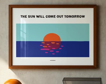 May include: A framed horizontal wall art print featuring a stylized orange sun setting over a dark blue sea against a light blue sky. The text THE SUN WILL COME OUT TOMORROW is printed in black at the top, with small text at the bottom center.