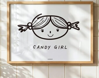 May include: A framed wall art print featuring a black line drawing of a face with pigtails and the text CANDY GIRL in a simple font. The artwork is enclosed in a light-colored wooden frame, presenting a clean, graphic illustration on a white background.