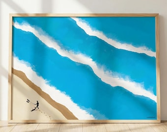 May include: A rectangular wall art print in a light wood frame featuring an aerial view of a sandy beach with bright blue ocean waves and white foam. A small black silhouette of a person walking with a kite is visible on the sand.
