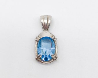 May include: A silver pendant featuring a light blue oval gemstone.