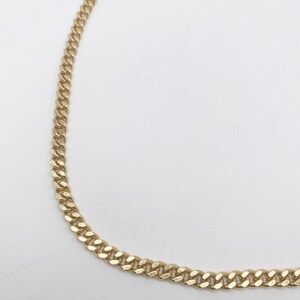 May include: A gold chain necklace with a curb link style.