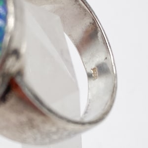 May include: Silver ring featuring a blue opal stone. The inside of the band is marked with the number "925", signifying sterling silver.