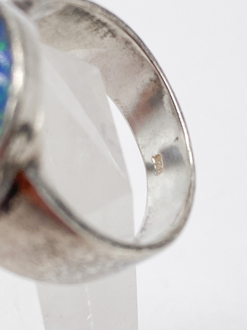 May include: Silver ring featuring a blue opal stone. The inside of the band is marked with the number "925", signifying sterling silver.