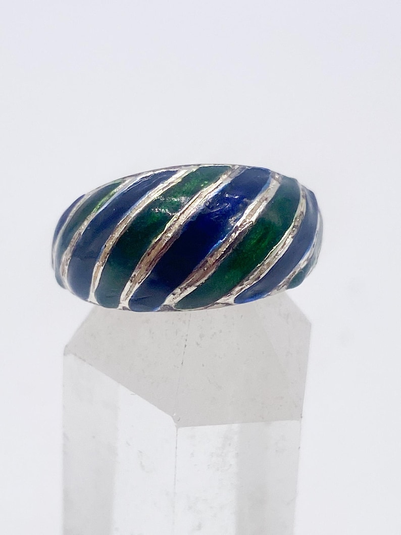 Puede incluir: Un anillo de plata con un dise&ntilde;o de esmalte colorido. El anillo presenta rayas alternas de esmalte azul y verde, creando un patr&oacute;n llamativo. Una pieza de joyer&iacute;a llamativa.