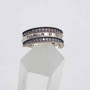 May include: A silver Pandora ring with a double row of clear cubic zirconia stones and the word "Pandora" engraved on the band.